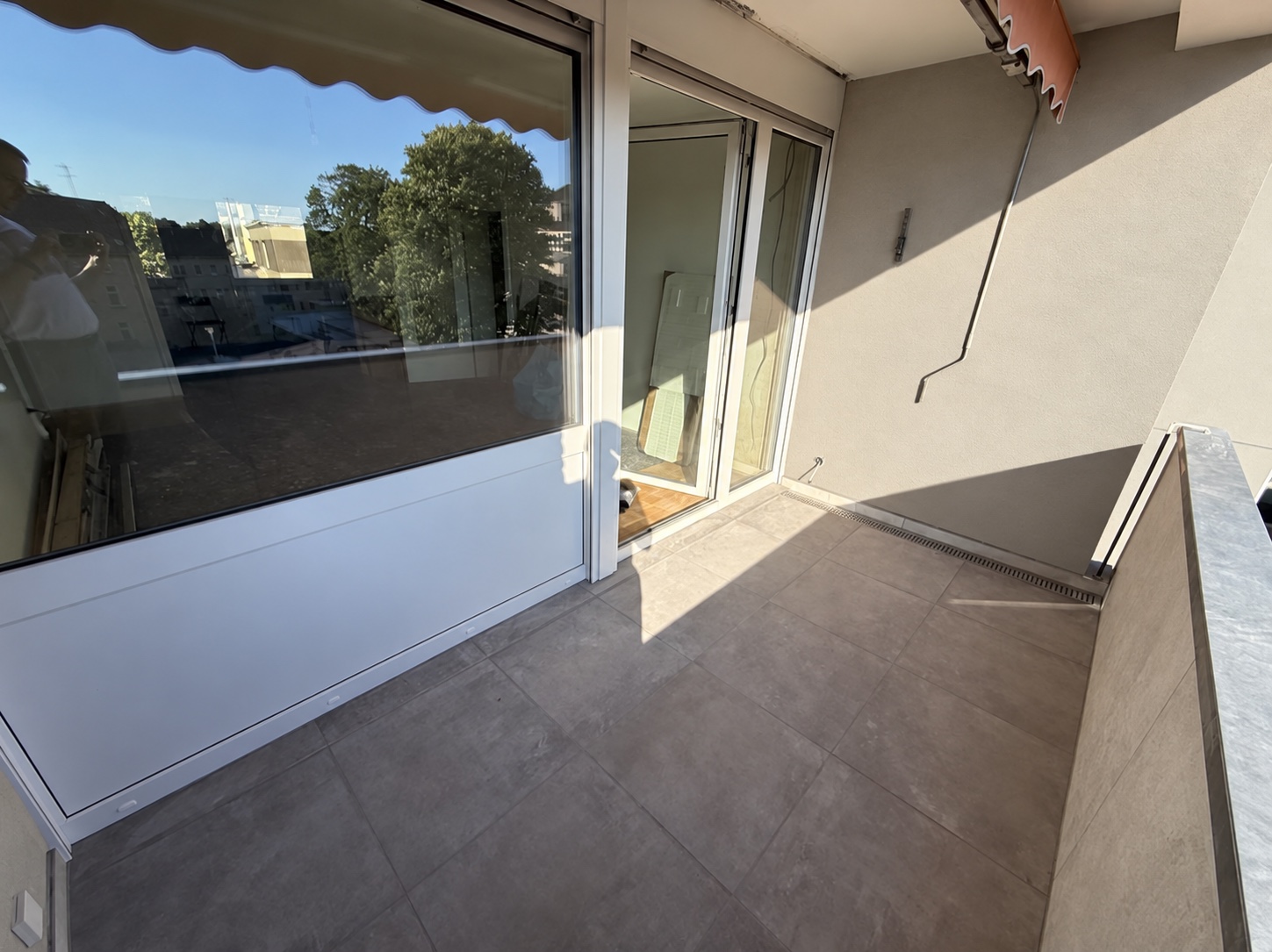 Balkon mit großformatigem Fliesenbelag und Entwässerungsrinne; Wandgestaltung digital verändert